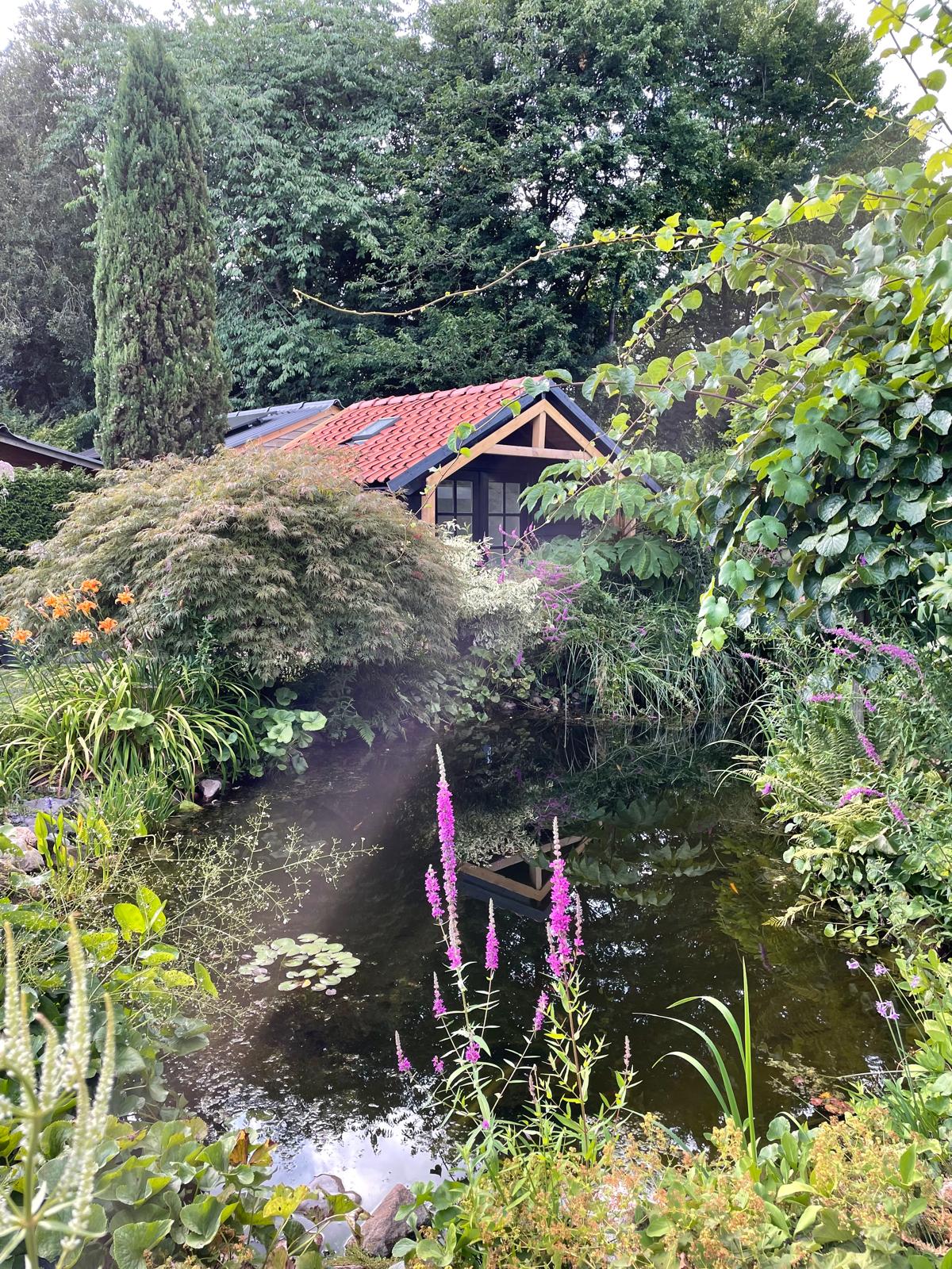 Tuinontwerper Peter Pijpker werkend aan een ontwerp in een weelderige tuin omgeving